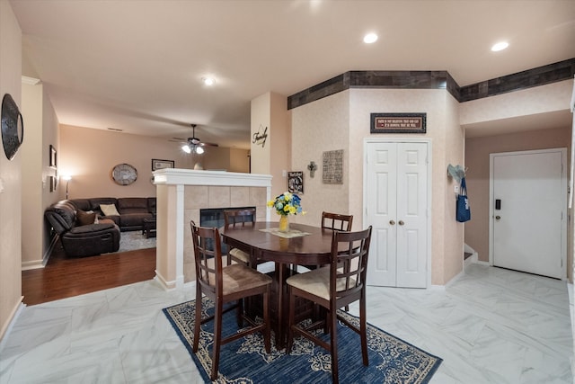 dining space with ceiling fan, recessed lighting, baseboards, marble finish floor, and a tiled fireplace