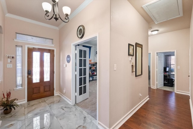 entrance foyer with ornamental molding, wood finished floors, baseboards, and an inviting chandelier