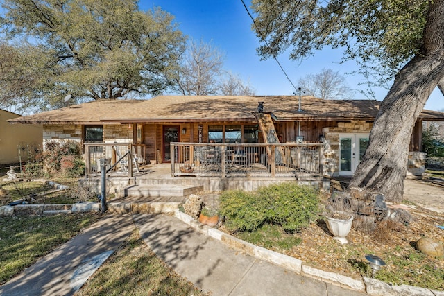 ranch-style house featuring covered porch, stone siding, and french doors