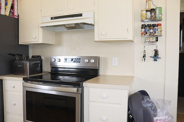 kitchen featuring white cabinets, stainless steel range with electric stovetop, under cabinet range hood, and light countertops