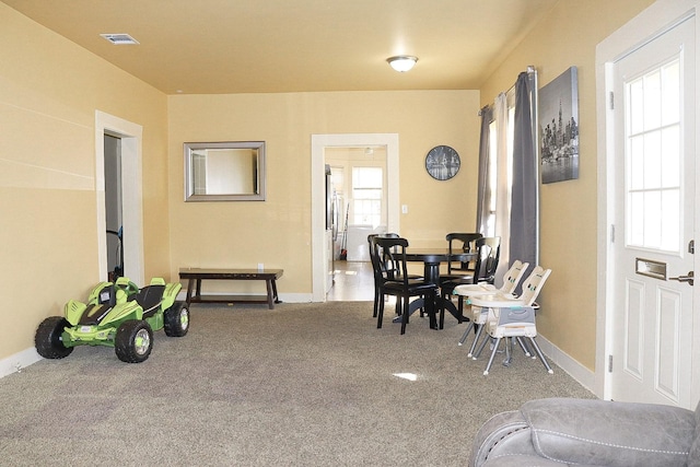 carpeted dining room with visible vents and baseboards