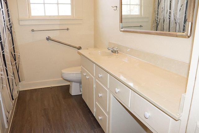 bathroom with a shower with shower curtain, toilet, vanity, wood finished floors, and baseboards