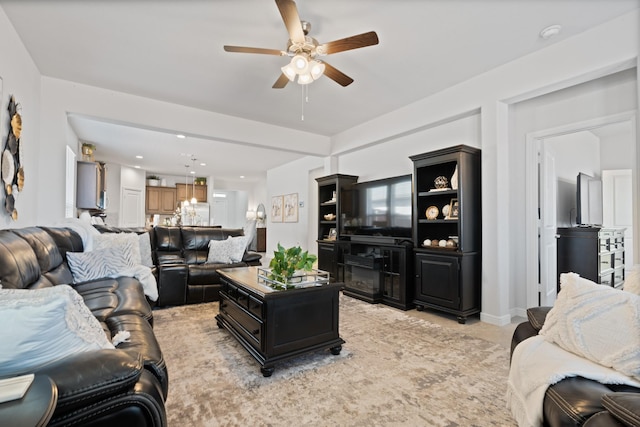 living area with ceiling fan, baseboards, and light colored carpet