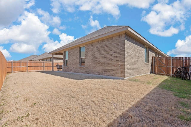 view of property exterior with a fenced backyard, a lawn, and brick siding