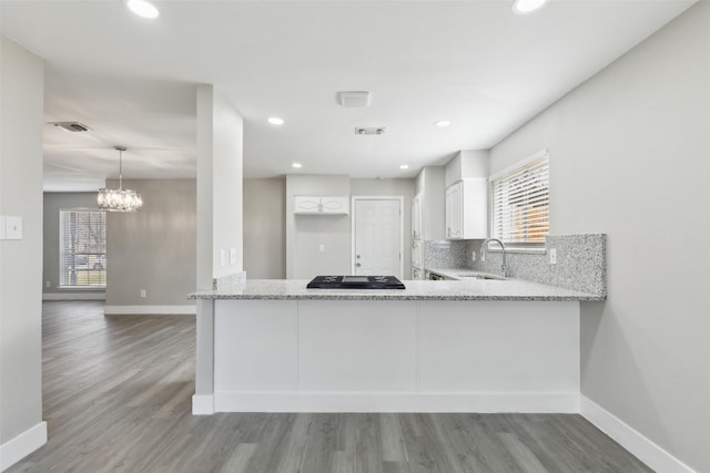 kitchen with tasteful backsplash, visible vents, a healthy amount of sunlight, white cabinetry, and light stone countertops