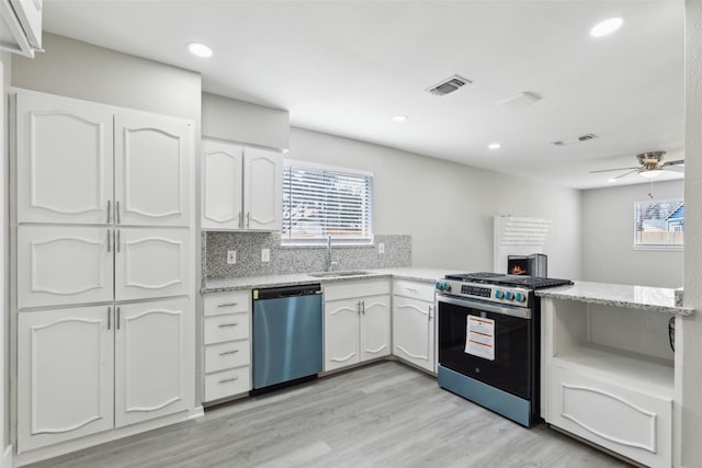 kitchen with backsplash, appliances with stainless steel finishes, light wood-style floors, white cabinets, and a sink