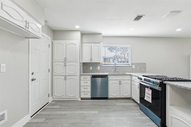 kitchen featuring appliances with stainless steel finishes, visible vents, a sink, and white cabinetry