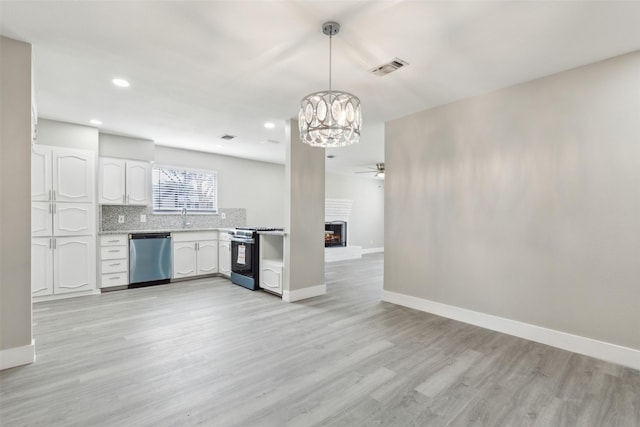 kitchen featuring white cabinets, light countertops, a brick fireplace, dishwasher, and range with gas cooktop