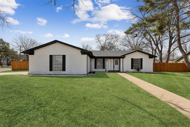 view of front of property featuring brick siding, a front lawn, and fence