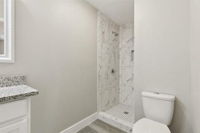 full bathroom with toilet, a stall shower, baseboards, and vanity