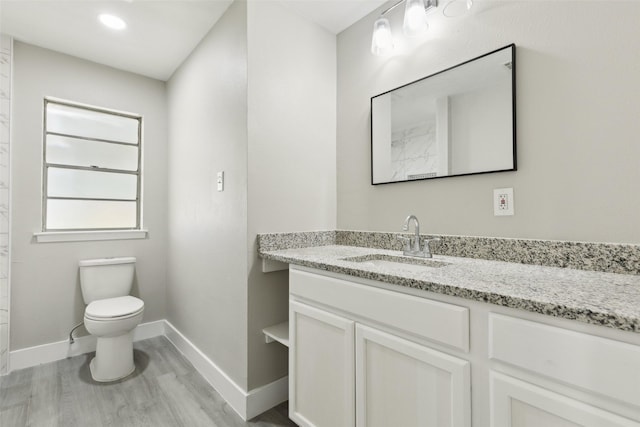 bathroom with baseboards, vanity, toilet, and wood finished floors