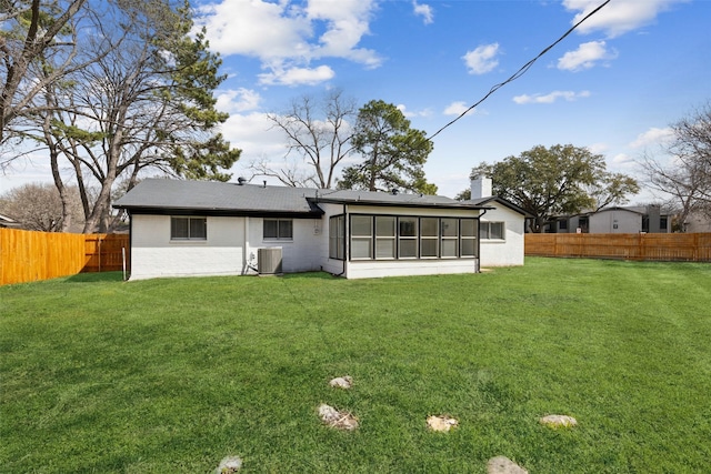 rear view of house featuring a chimney, a fenced backyard, a yard, and central AC