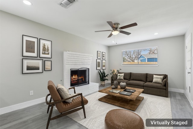 living room featuring visible vents, a fireplace, baseboards, and wood finished floors