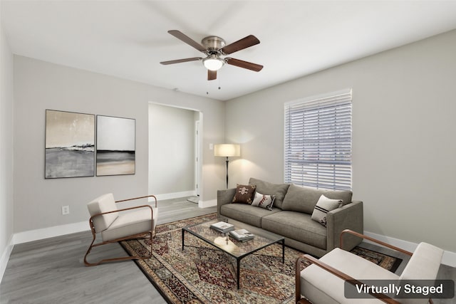 living area featuring a ceiling fan, baseboards, and wood finished floors