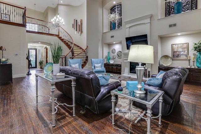 living room with visible vents, arched walkways, wood finished floors, stairs, and a notable chandelier