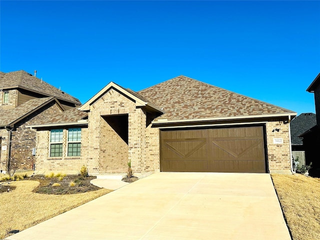 view of front of house featuring concrete driveway, brick siding, an attached garage, and roof with shingles