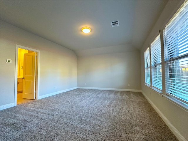 carpeted empty room featuring lofted ceiling, visible vents, and baseboards