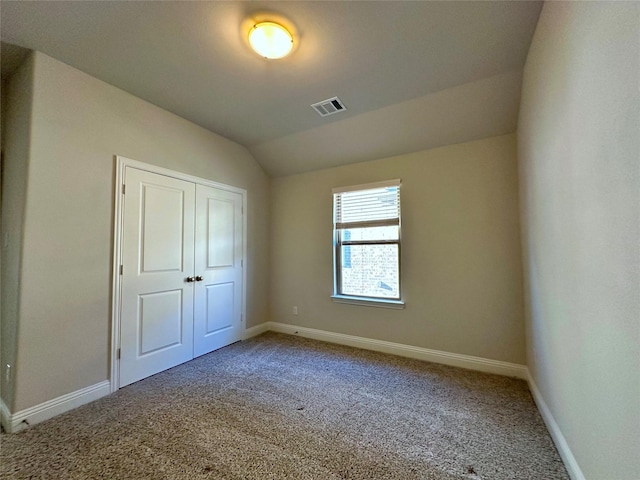 unfurnished bedroom with visible vents, baseboards, carpet, vaulted ceiling, and a closet