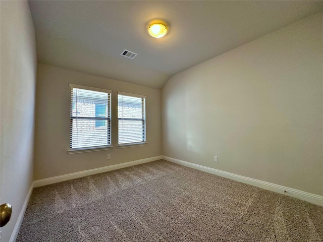 carpeted spare room with lofted ceiling, visible vents, and baseboards