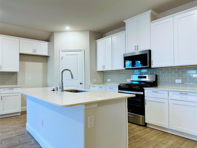 kitchen featuring wood finish floors, backsplash, appliances with stainless steel finishes, a kitchen island with sink, and a sink