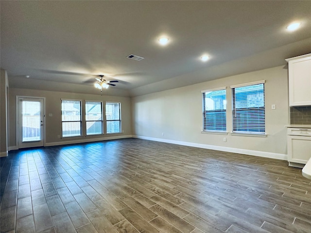 unfurnished living room with ceiling fan, dark wood-style flooring, visible vents, and baseboards