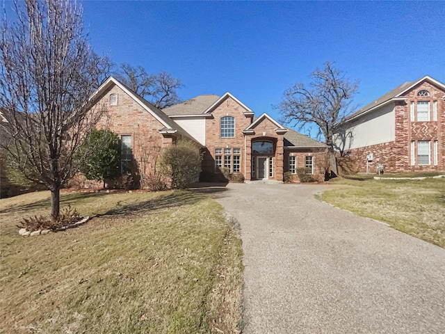 view of front of home featuring brick siding, a front yard, and aphalt driveway