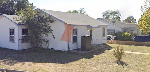 view of property exterior featuring fence and a lawn