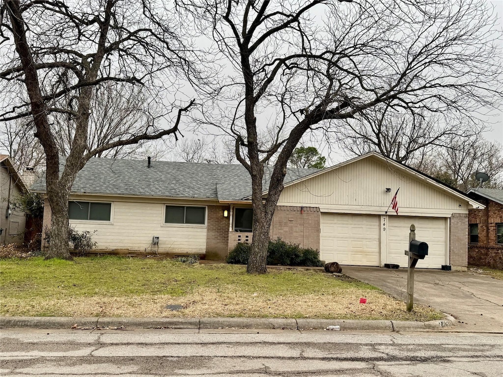 ranch-style house with a front yard, brick siding, driveway, and an attached garage