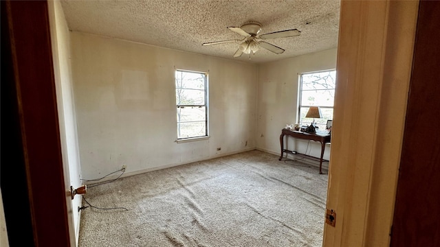 empty room with carpet, a textured ceiling, baseboards, and a ceiling fan