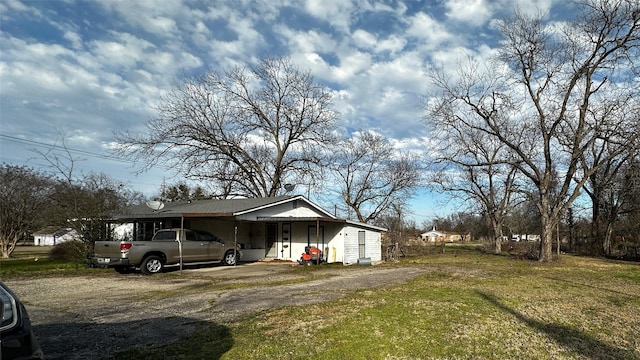 view of side of home with driveway, a carport, and a lawn