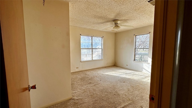 empty room with a textured ceiling, carpet flooring, visible vents, baseboards, and a ceiling fan