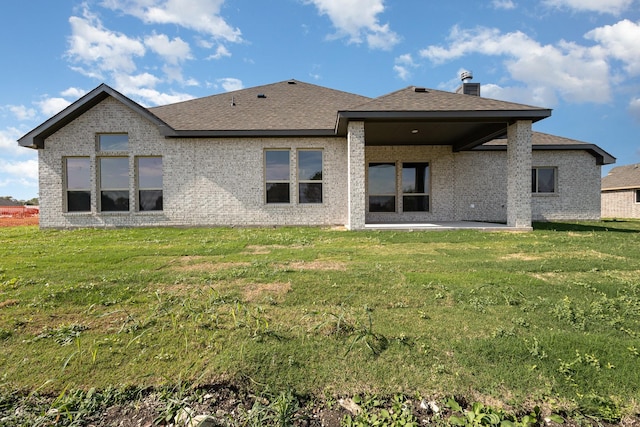 rear view of property with a patio area, brick siding, and a yard