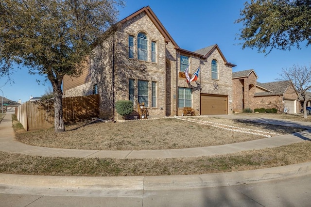 traditional-style home featuring driveway, brick siding, an attached garage, and fence