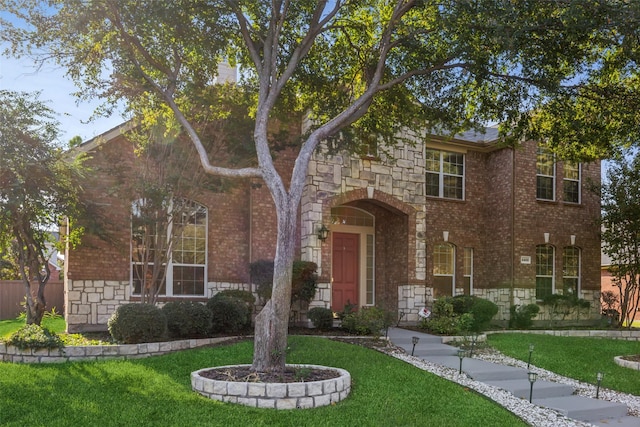 view of front facade featuring stone siding, brick siding, and a front lawn