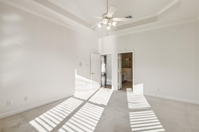 unfurnished room with a tray ceiling, light colored carpet, visible vents, and baseboards