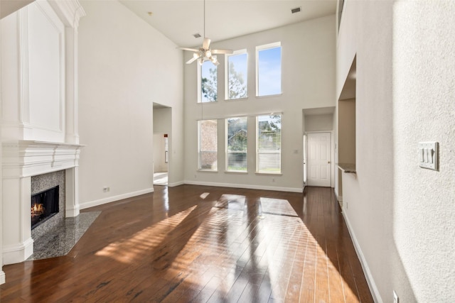 living room featuring a high end fireplace, visible vents, baseboards, and hardwood / wood-style flooring