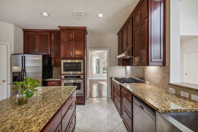 kitchen featuring reddish brown cabinets, visible vents, appliances with stainless steel finishes, stone countertops, and under cabinet range hood