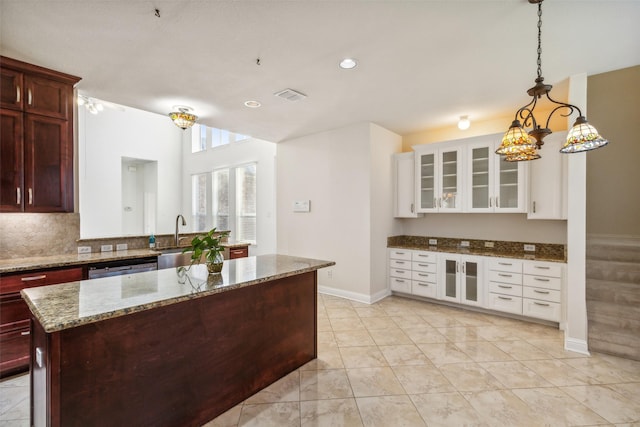 kitchen with visible vents, dishwashing machine, glass insert cabinets, light stone counters, and a sink