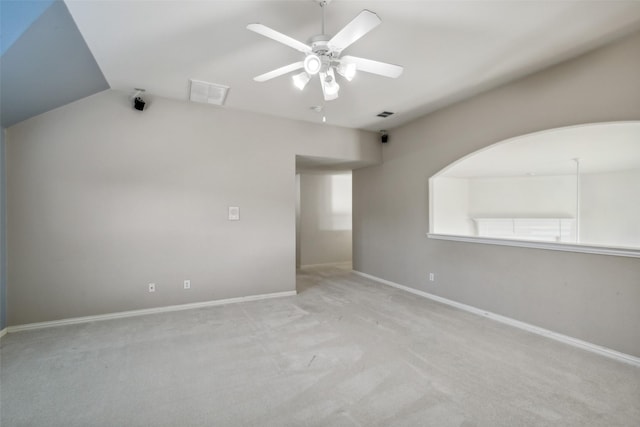 carpeted spare room with vaulted ceiling, visible vents, ceiling fan, and baseboards