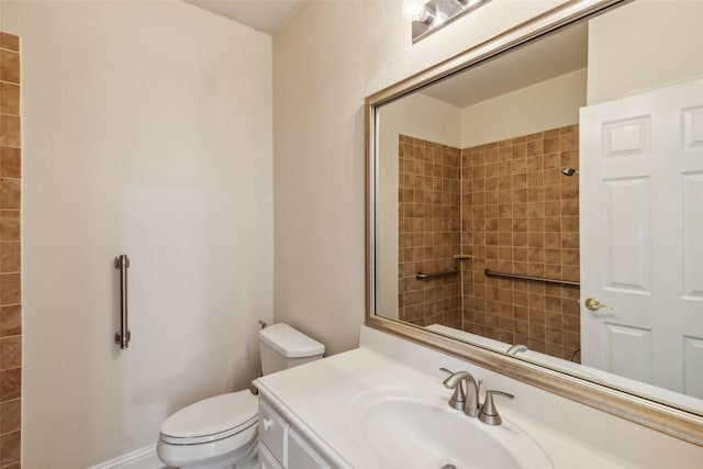 bathroom with a tile shower, vanity, and toilet