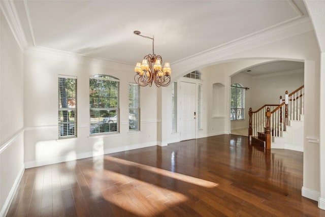 unfurnished dining area featuring arched walkways, a notable chandelier, wood finished floors, stairs, and ornamental molding