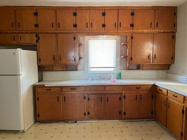 kitchen with freestanding refrigerator, light countertops, a sink, and light floors