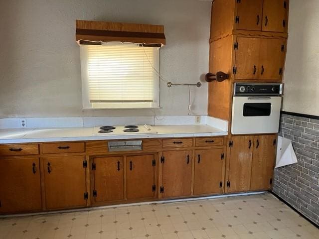 kitchen featuring white appliances, light countertops, light floors, and brown cabinetry