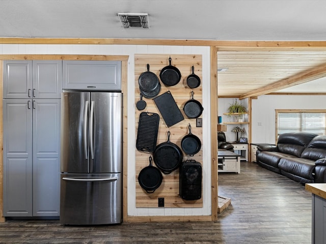 kitchen with dark wood-style floors, wooden walls, visible vents, and freestanding refrigerator