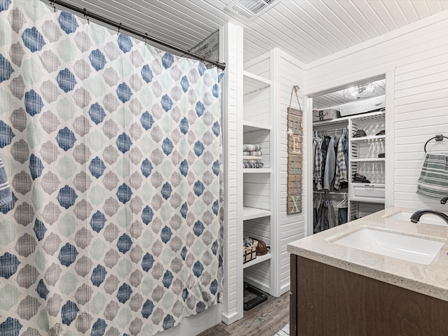 full bath featuring a shower with shower curtain, wood finished floors, vanity, visible vents, and a walk in closet