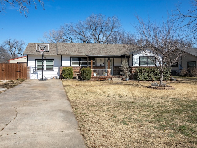 ranch-style home featuring covered porch, a front lawn, fence, and brick siding