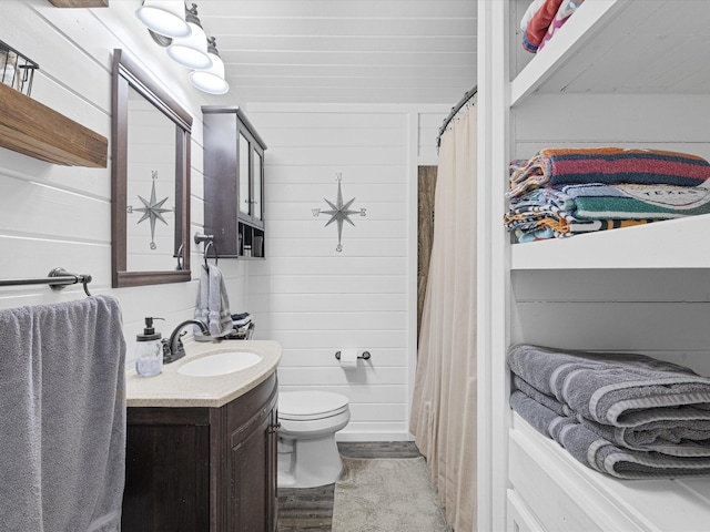 bathroom featuring toilet, curtained shower, vanity, and wooden walls