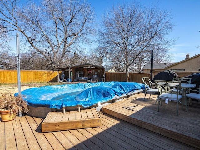 deck featuring a fenced in pool, outdoor dining area, and a fenced backyard