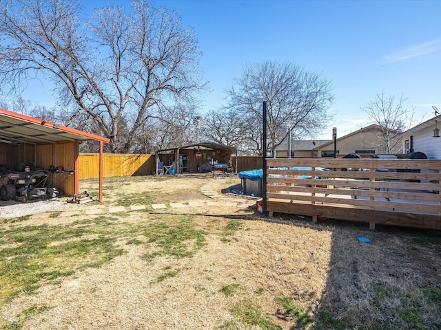 view of yard with a wooden deck, fence, and an outbuilding