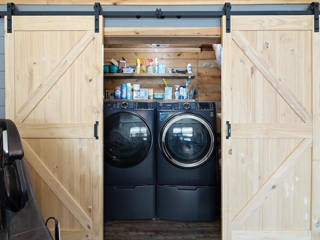 laundry room featuring wood finished floors, laundry area, a barn door, and washing machine and dryer